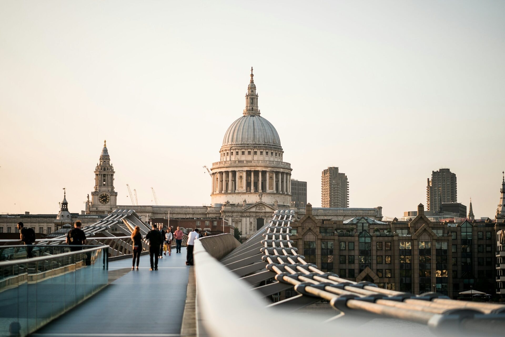 Pedestrians crossing the Millennium Bridge towards St Paul's Cathedral at sunset