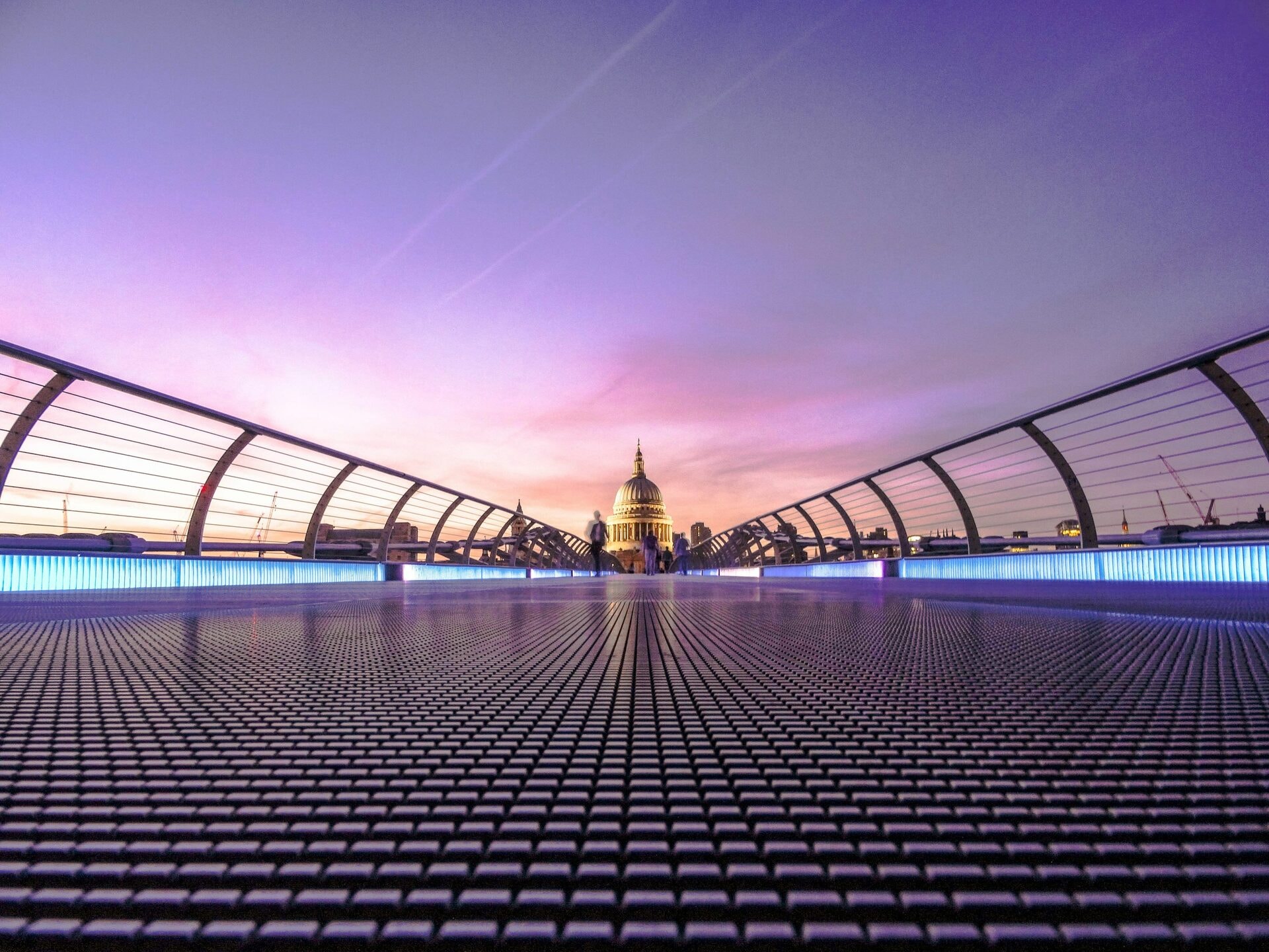 Pedestrians crossing the Millennium Bridge towards St Paul's Cathedral at dusk