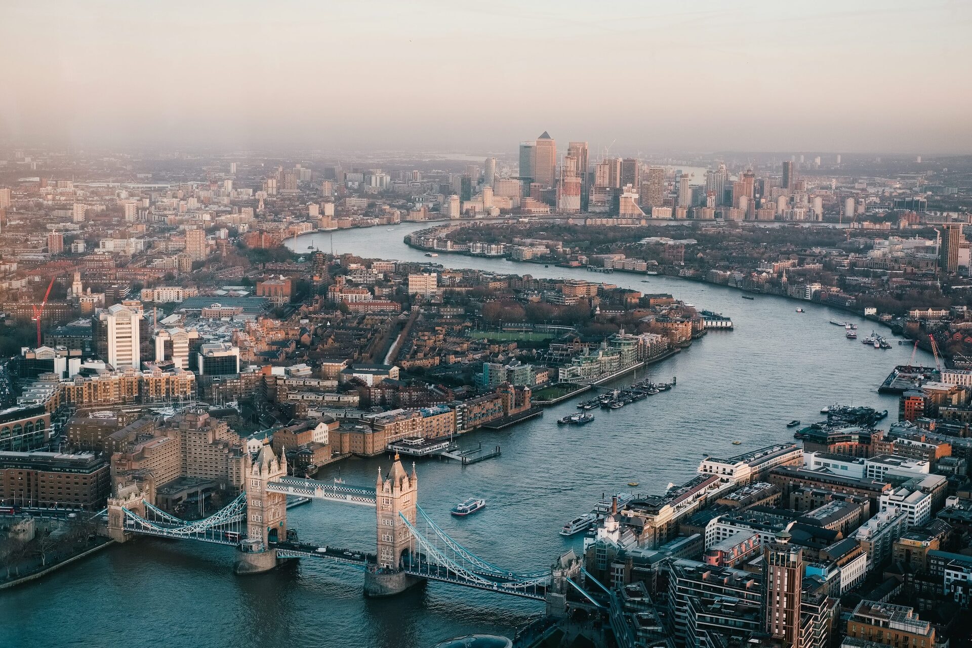 Aerial view of Tower Bridge and the River Thames curving through London at sunset